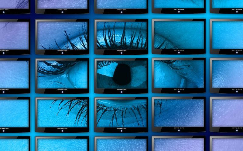 Un oeil affiché sur un mur d'écrans bleu-violet